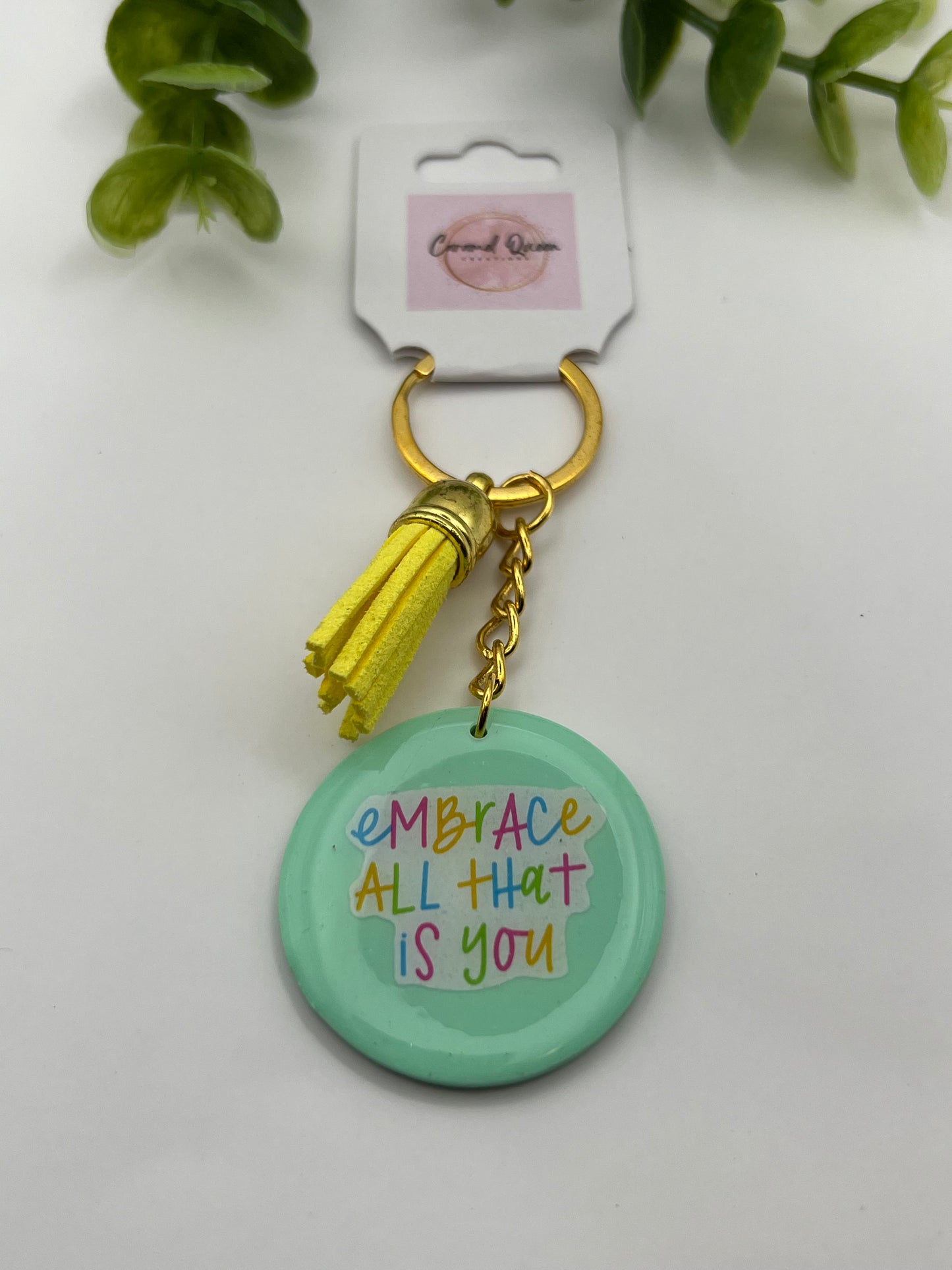 Mint green "embrace" keychain with yellow tassel